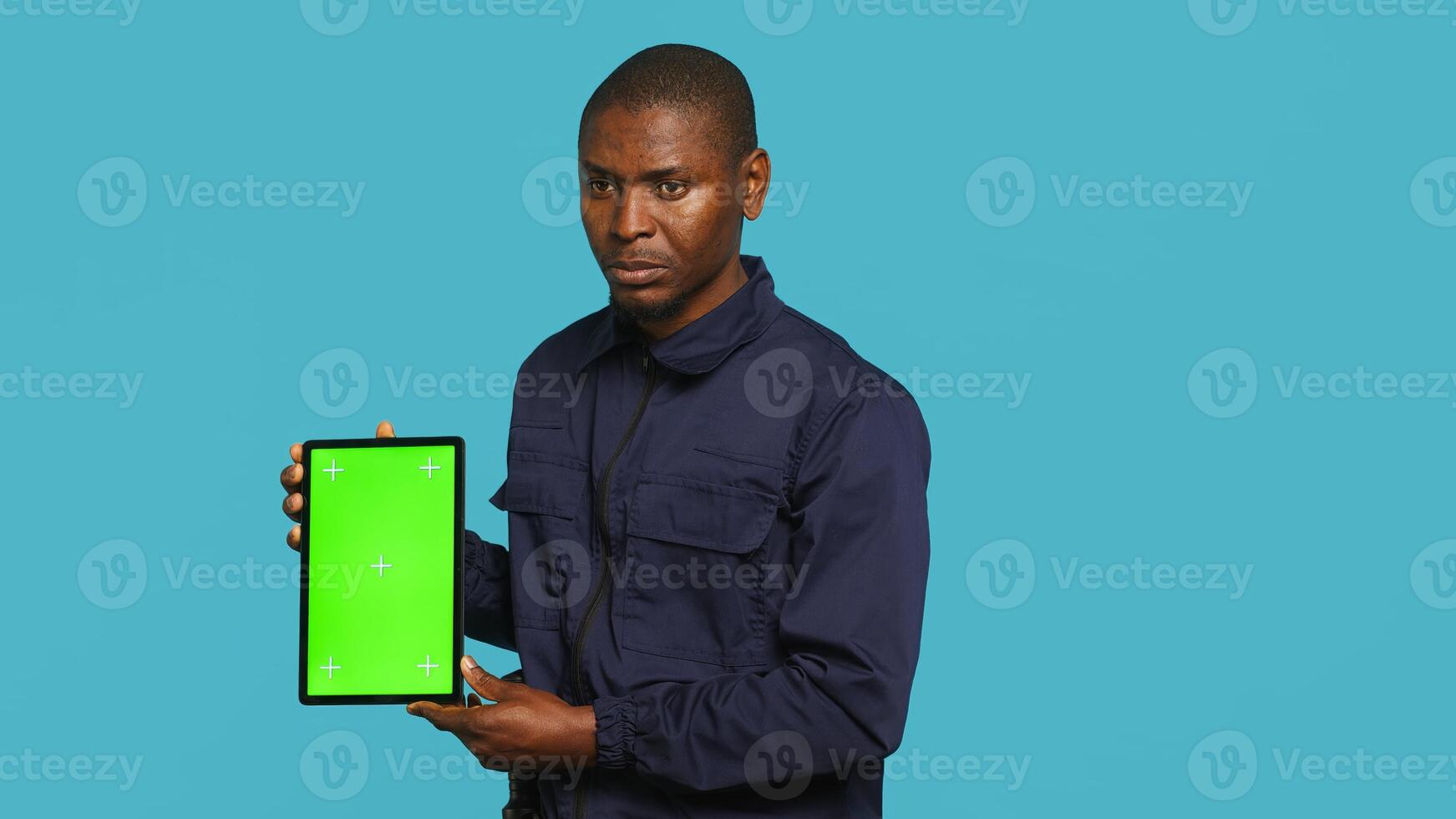 Security guard holding clock, rushing people out of property. Portrait of stern bodyguard showing visitors time is passing, preparing for closing down location, studio background, camera A photo