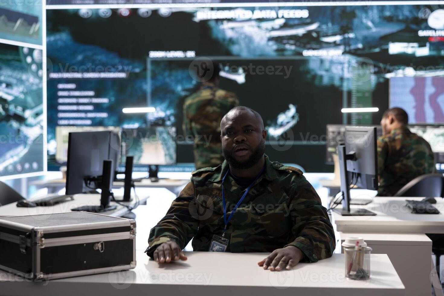 Military intelligence expert conducts a strategic teleconference connection in a modern command post, utilizing real time data on multiple screens for effective communication and decision making. photo