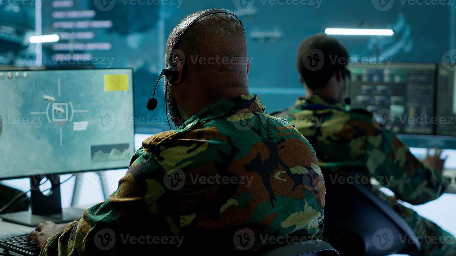 Military personnel in a base of operations using advanced computers and big screen, monitoring satellite systems to enhance security measures and process data. High tech army gear. Camera A. photo