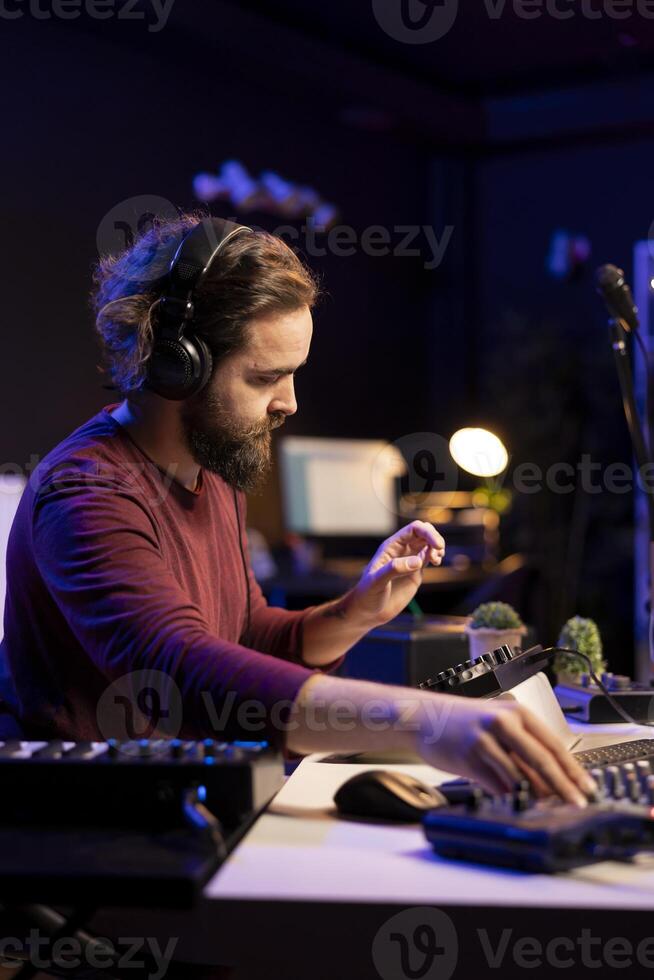 Audio engineer using stereo console to add sound effects on songs, working with daw software on pc for post production. Composer songwriter producing new tracks with amplifier and recordings. photo