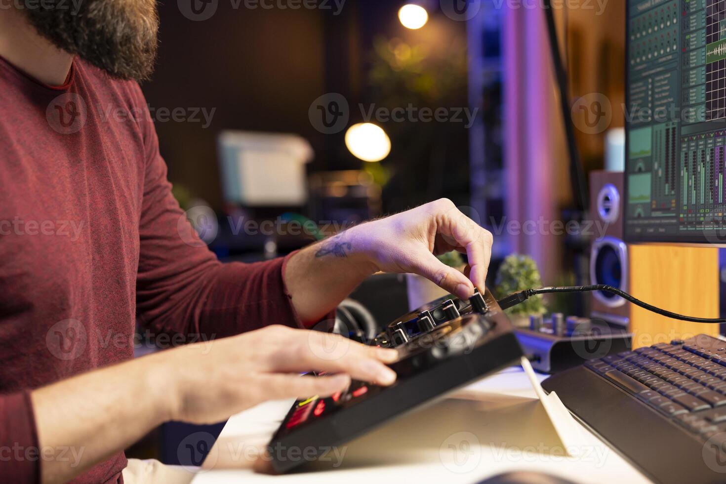 Composer artist twisting pre amp knobs and adjusting volume levels in home studio, mixing and mastering tunes for post production. Young singer recording and editing soundtracks. photo
