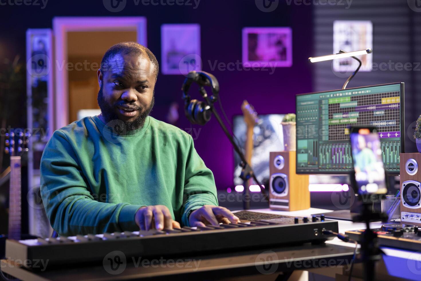 Artist songwriter hosting online master class to teach piano lessons on internet vlog, explaining electronic keyboard notes in his home studio. Young composer playing on synthesizer, recording . photo