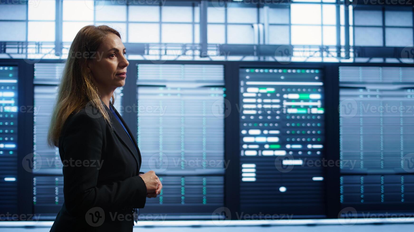 Engineer walking in data center workspace, monitoring systems to identify root cause of errors. Woman in server hub establishment doing diagnosis, looking for equipment bugs needing repairs, camera B photo