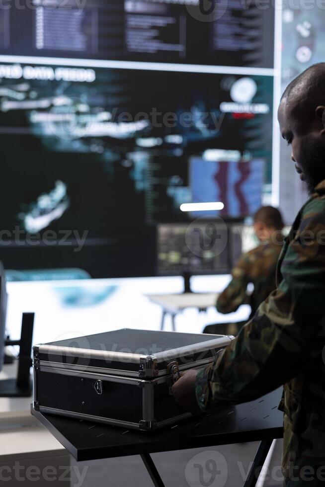 Army soldier handles satellite radar real time data on laptop in command post, coordinates strategic missions to support national defense operations in a high tech military base. Close up. photo