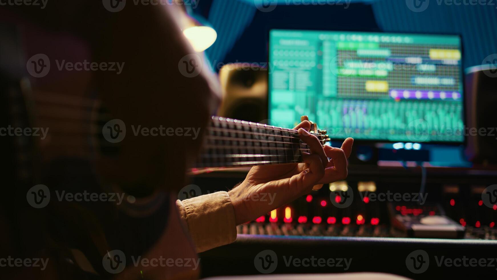 Skilled artist guitarist recording a new song with electro acoustic guitar, composing and editing music in professional studio control room. Young musician songwriter creating tunes. Camera A. photo