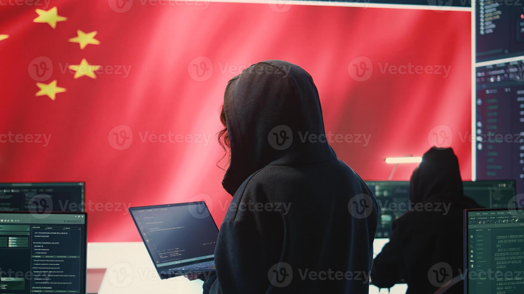 Chinese hacker working in governmental hacking room with Chinese flag on a big screen. Having the mission on inflicting fear and misinformation among the population. Dictatorship propaganda. Camera B. photo