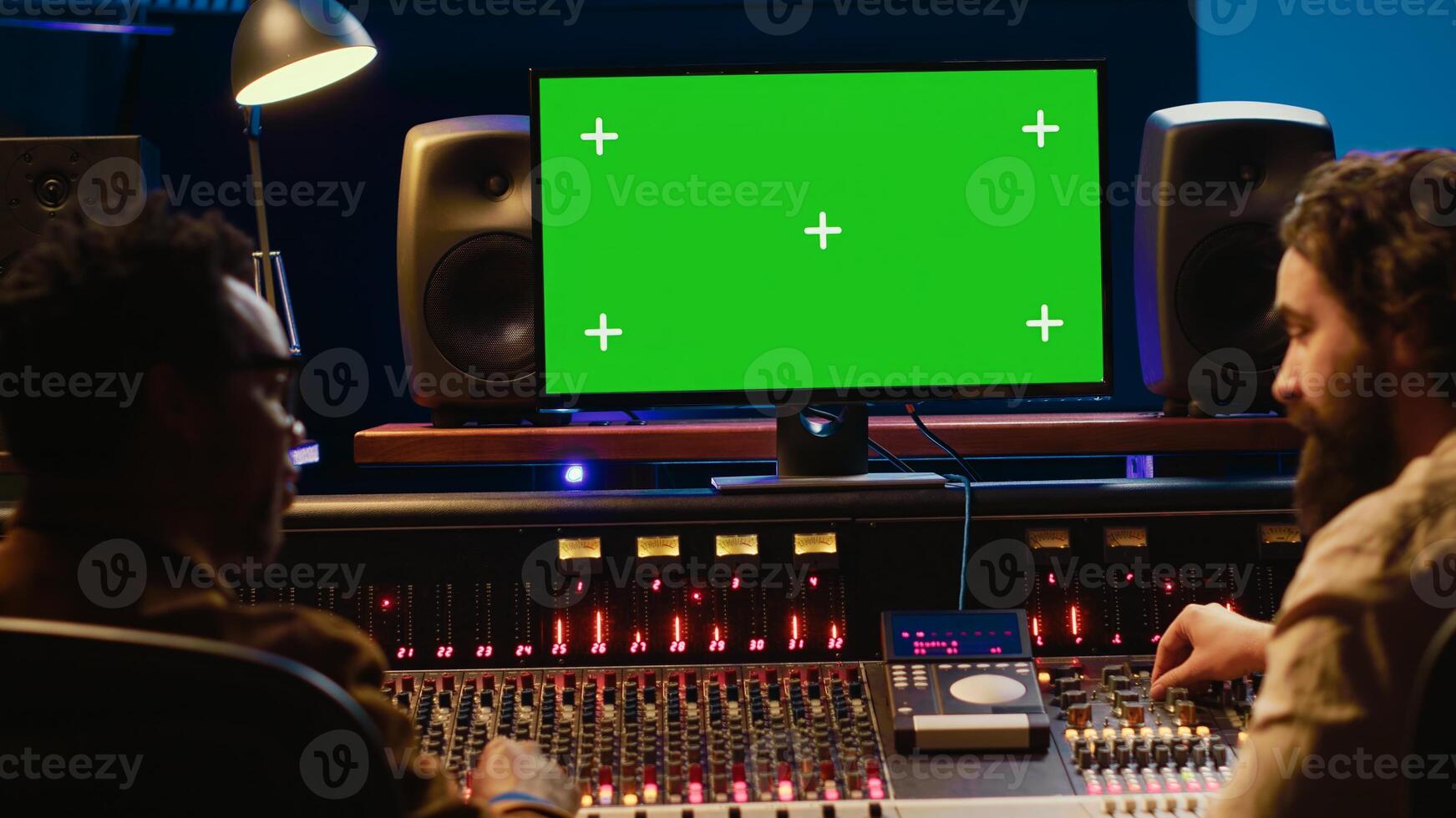 Diverse producers mixing and mastering tracks with mockup display on computer, recording before adding effects in post production. Artist and sound engineer twisting control desk knobs. Camera A. photo