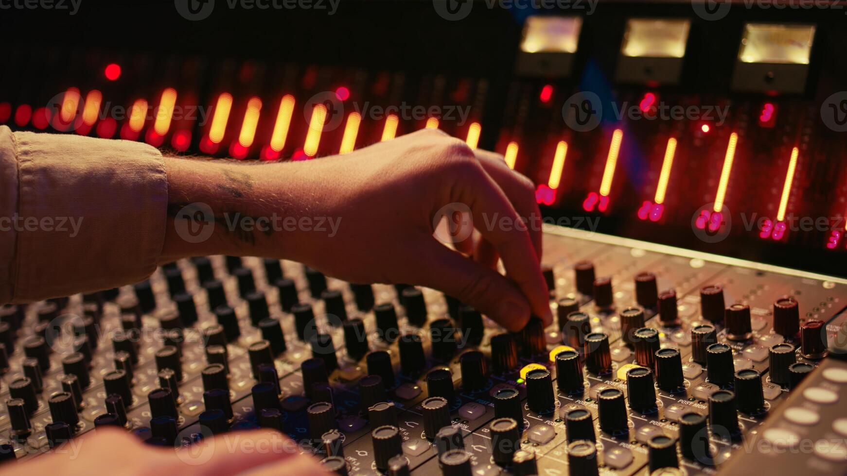 Audio technician twisting pre amp knobs and buttons on panel board in control room, using editing console for mixing and mastering tracks. Professional tracking engineer in music studio. Camera B. photo