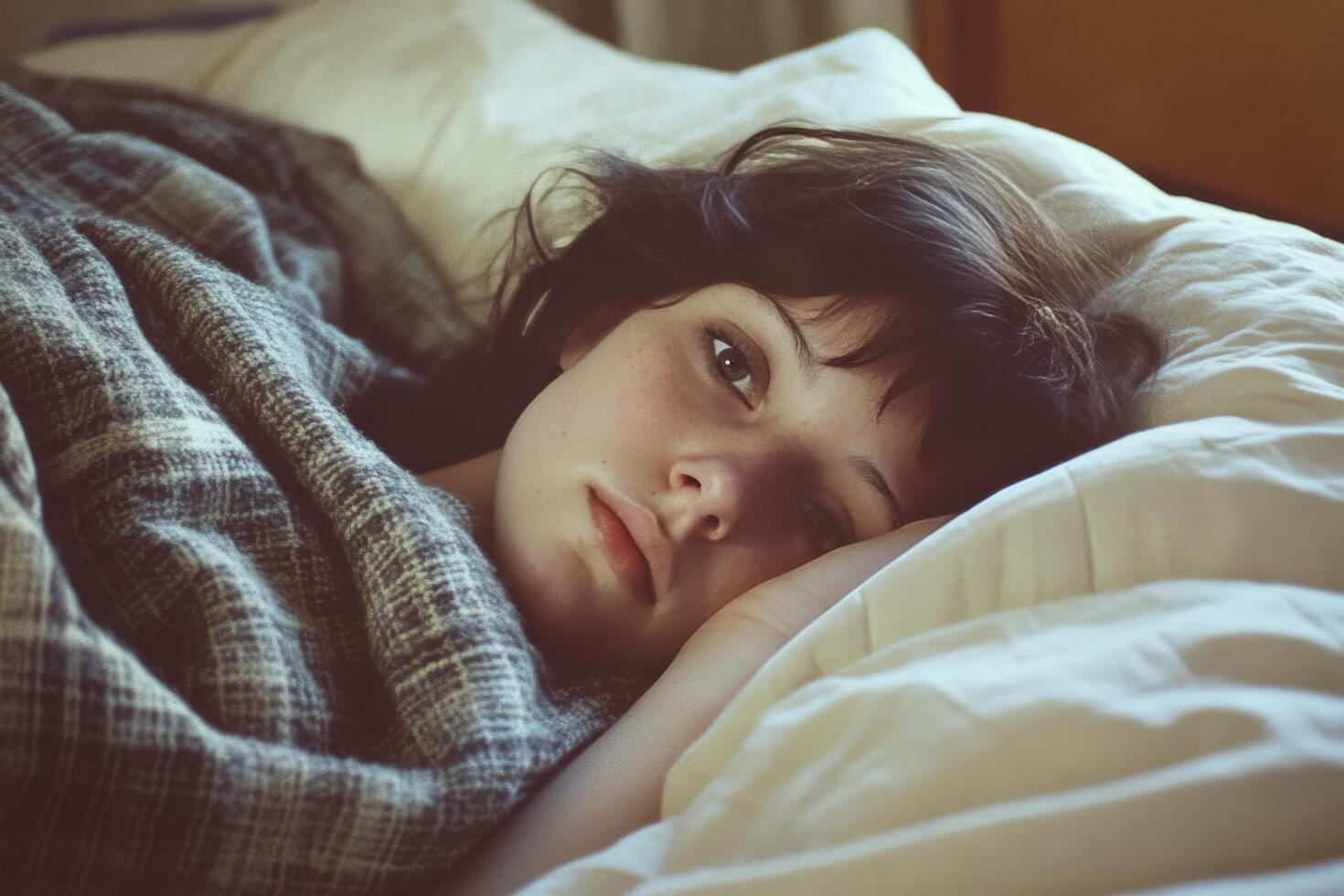 A young woman is laying in bed with her eyes closed photo