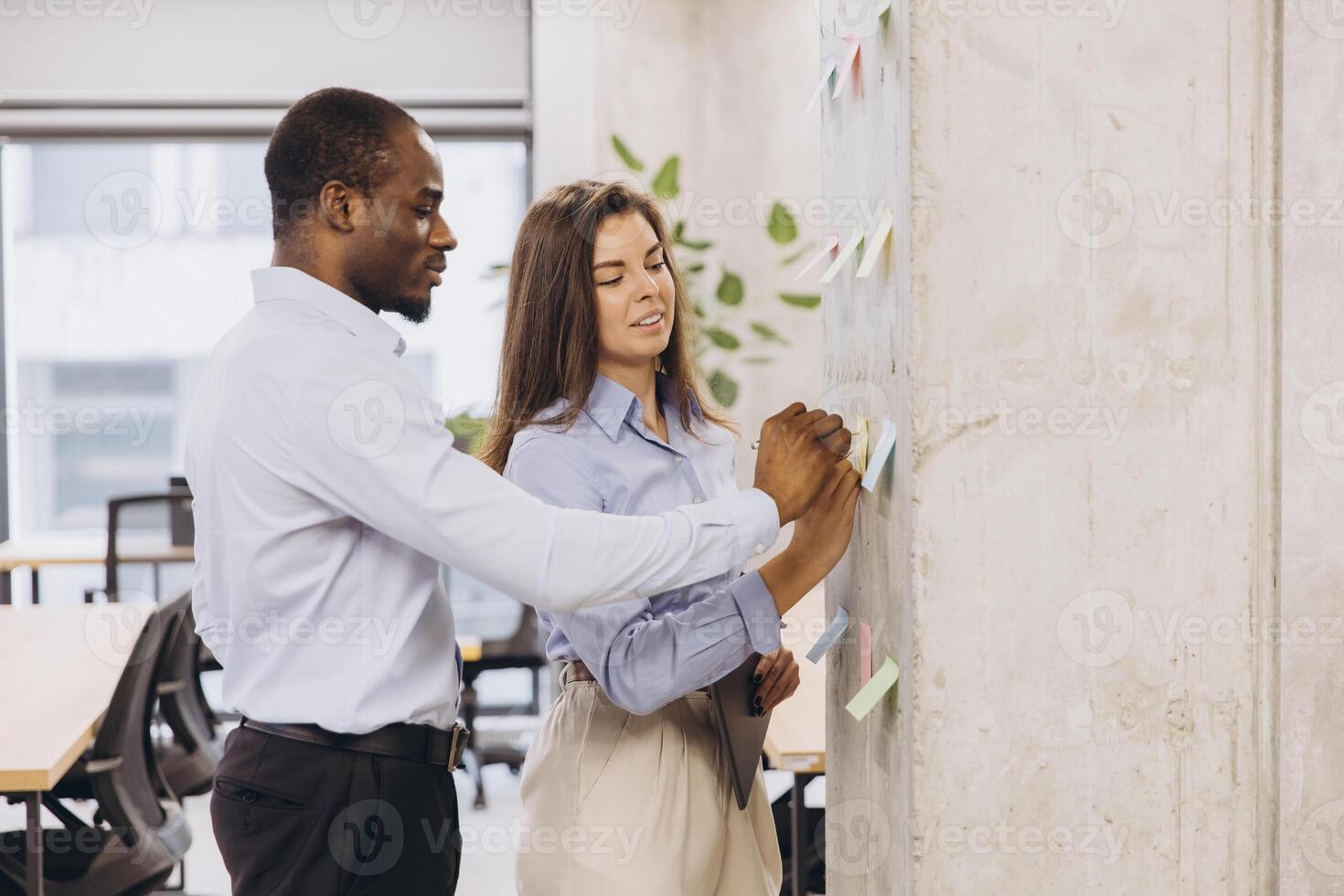 Business colleagues collaborating, using sticky notes on a wall in a modern office environment photo