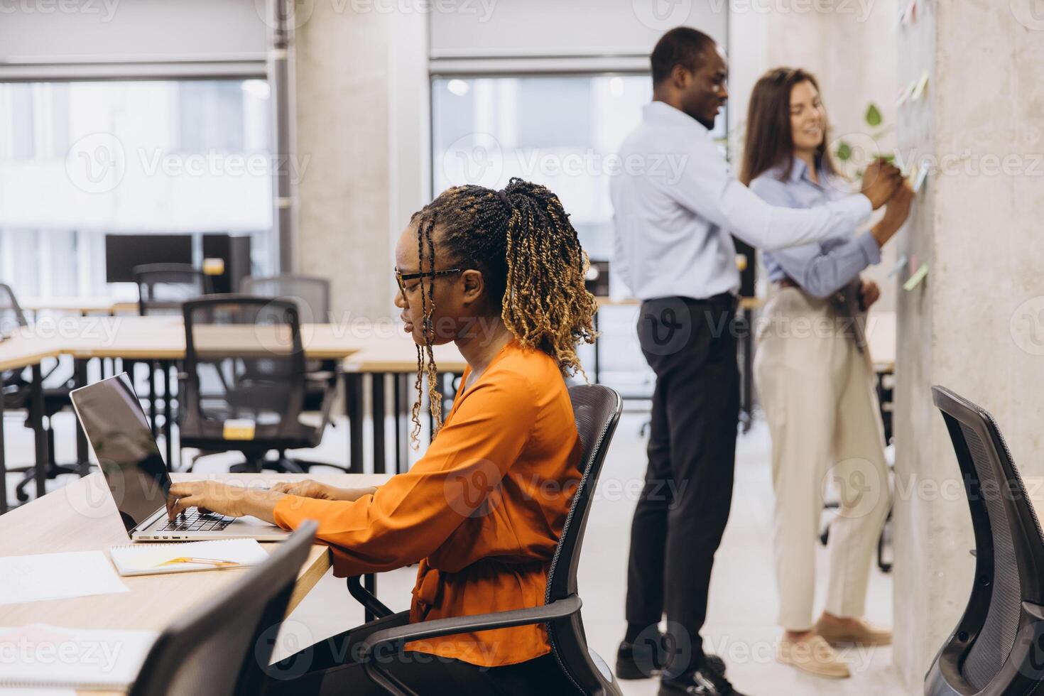 Colleagues collaborating, working individually and together in contemporary workspace, displaying team synergy and creative professional interaction photo
