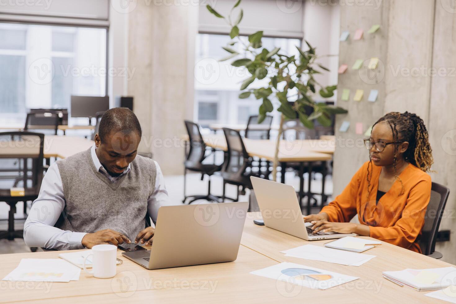 Diverse business team collaborating, using laptops and brainstorming strategic plans in modern, vibrant office environment photo