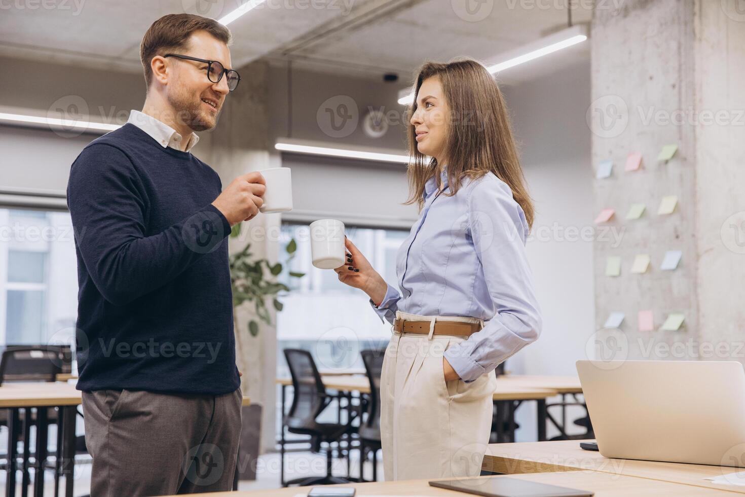 Colleagues conversing, holding coffee mugs near workspace with contemporary design photo