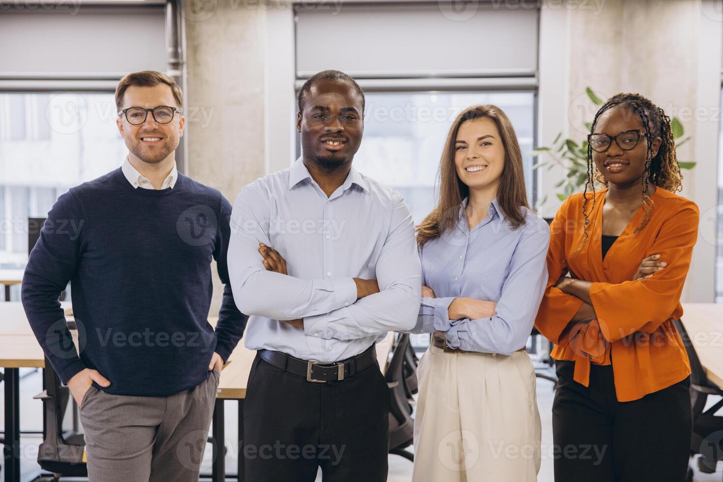 Multi ethnic businesspeople standing together with arms crossed, showing teamwork and confidence in a bright office environment photo