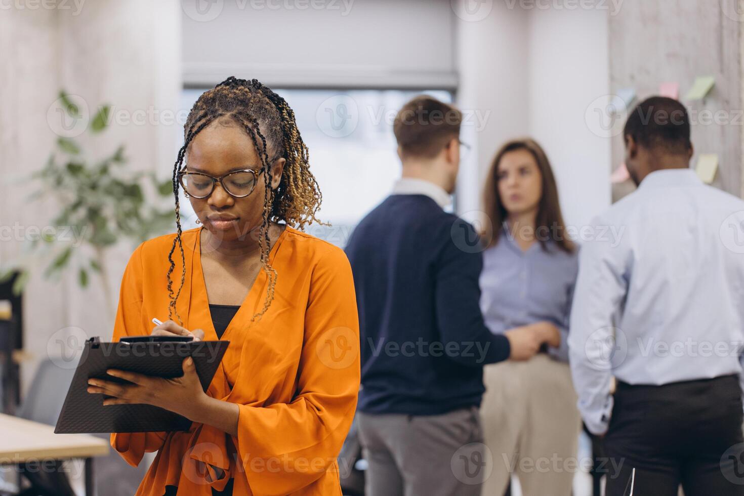 African american businesswoman holding a folder, professional team collaborating, working together in sleek open plan workspace, representing multicultural corporate synergy photo