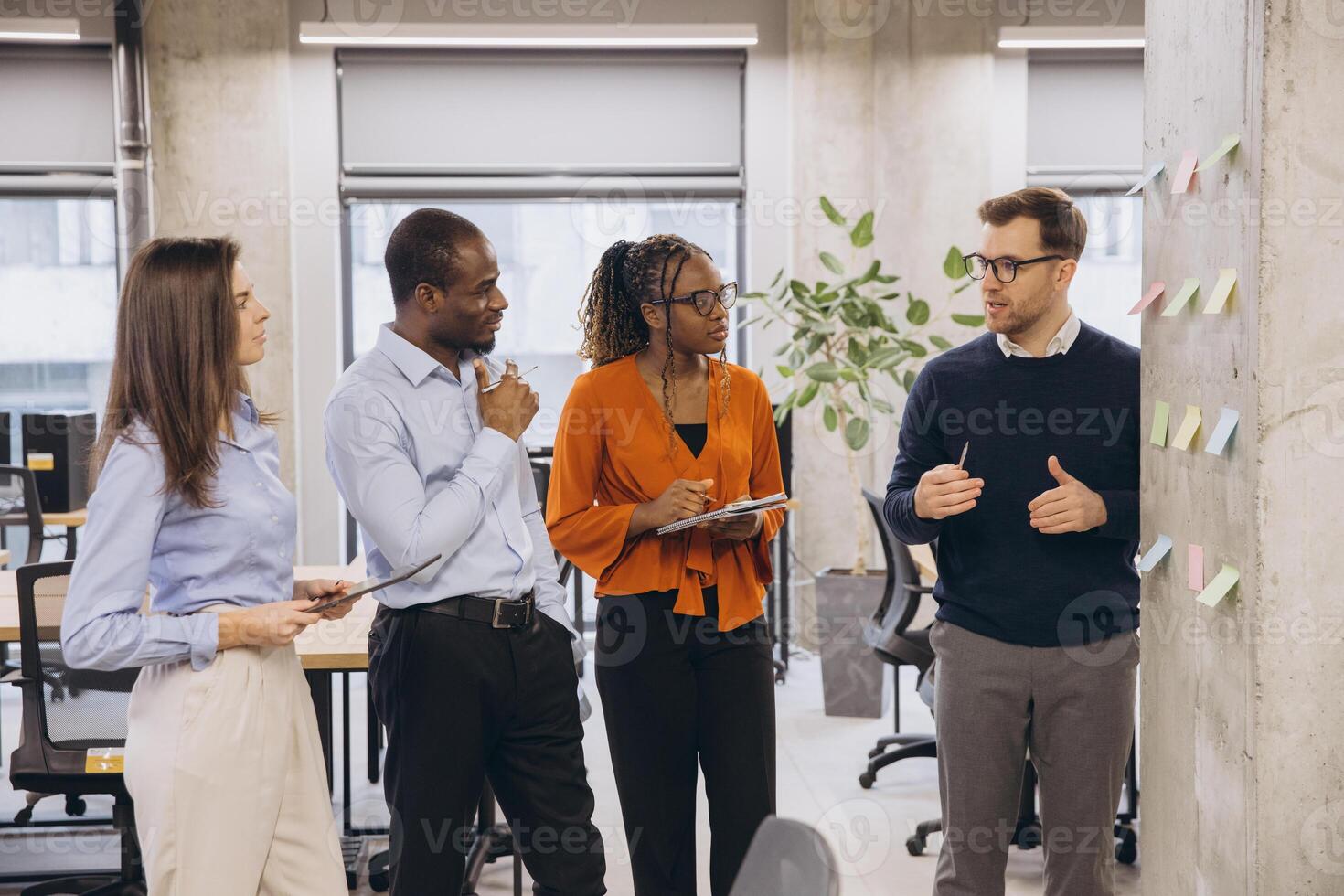 Group of diverse business people discussing new ideas using sticky notes during a productive meeting in a modern office environment photo