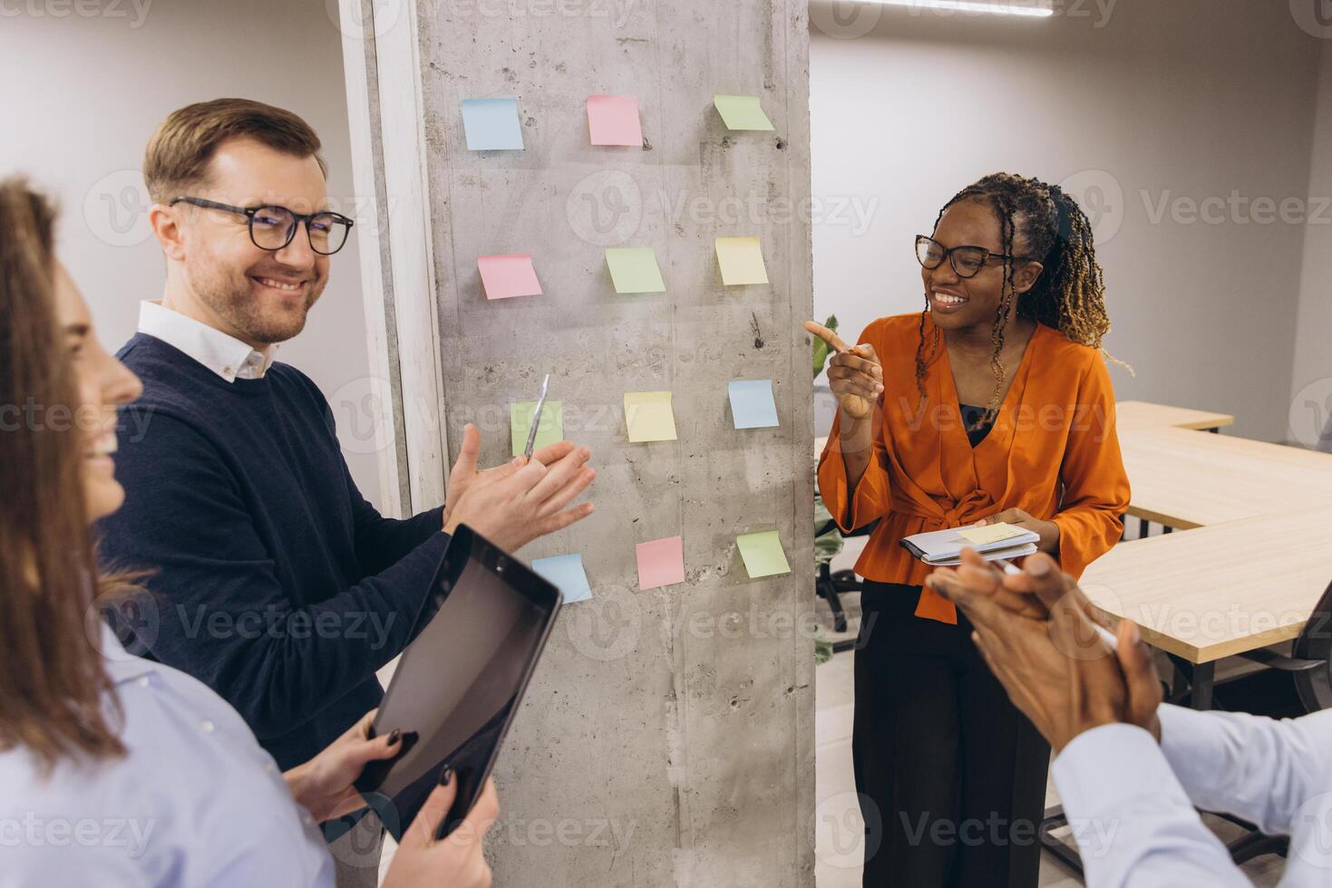 Collaborative team analyzing project strategy, placing multicolored sticky notes on glass wall in bright modern office setting photo