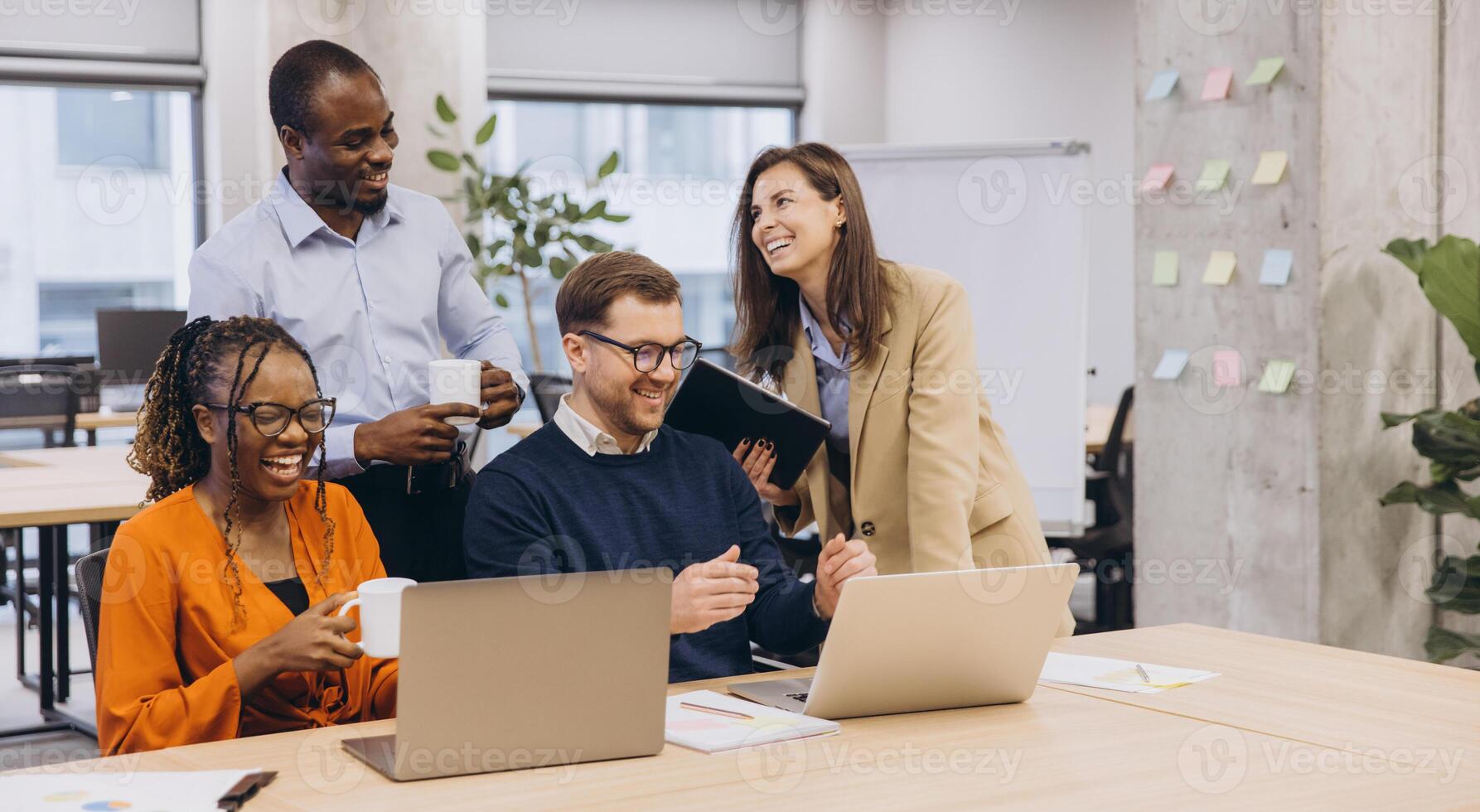Professional team collaborating, sharing insights across laptops, representing multicultural workplace dynamics with energy and connectivity photo