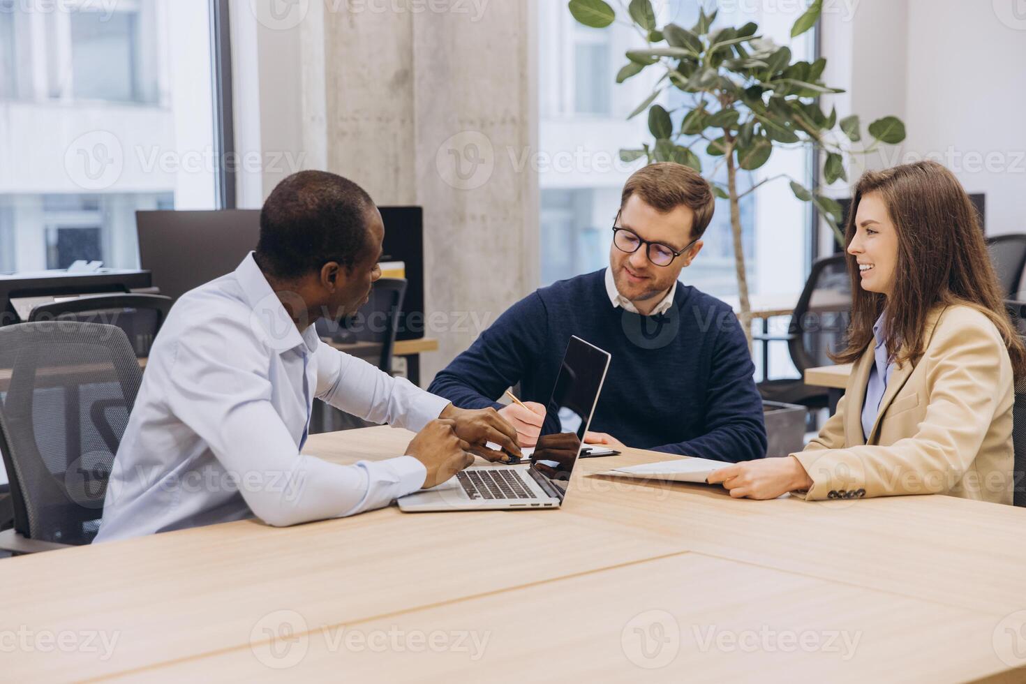 Professional team collaborating during strategic planning meeting, working together on laptops and sharing business documents in modern workspace photo