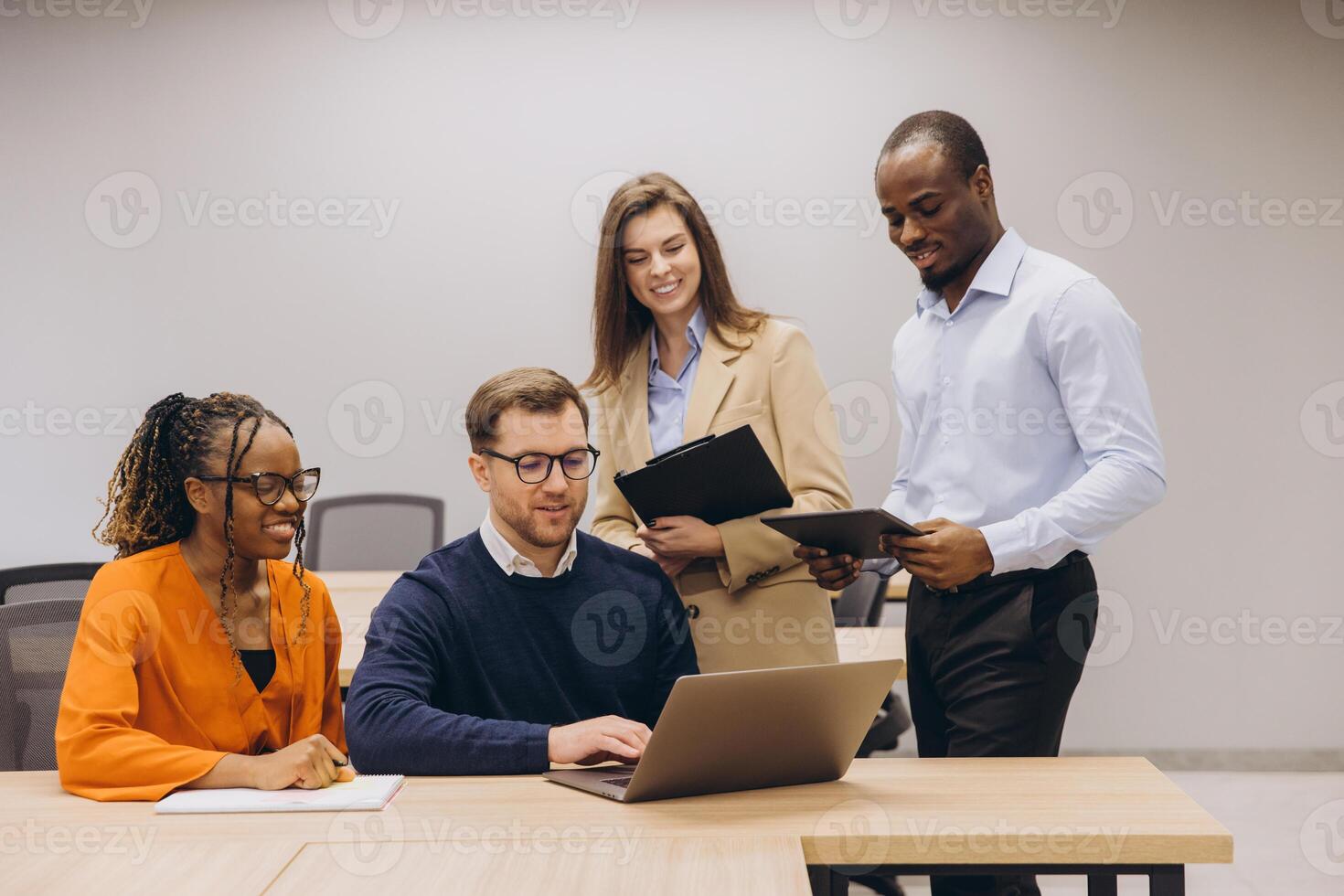 Professionals collaborating through digital devices, working together in modern, bright office space with diverse team members photo