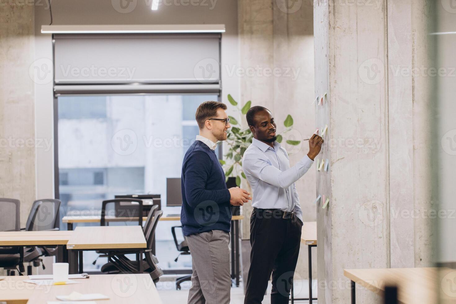 Professional colleagues collaborating near whiteboard, brainstorming strategic business solutions in modern workplace environment photo
