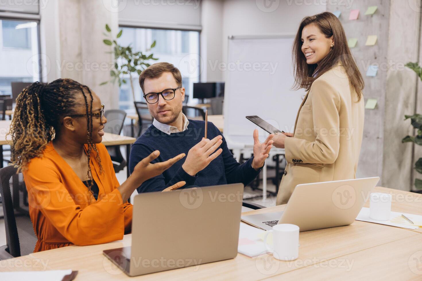 Professional team collaborating during high tech meeting, sharing insights using laptops and digital technology in modern workspace photo
