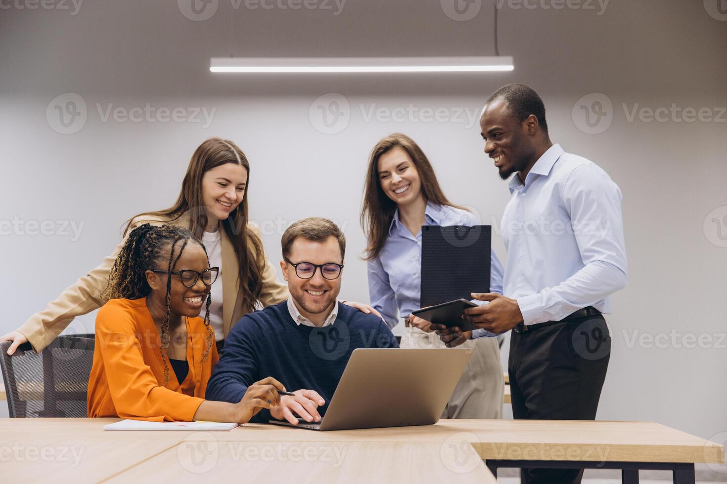 Professional team collaborating, leaning over laptop, sharing insights during productive meeting in contemporary workspace photo