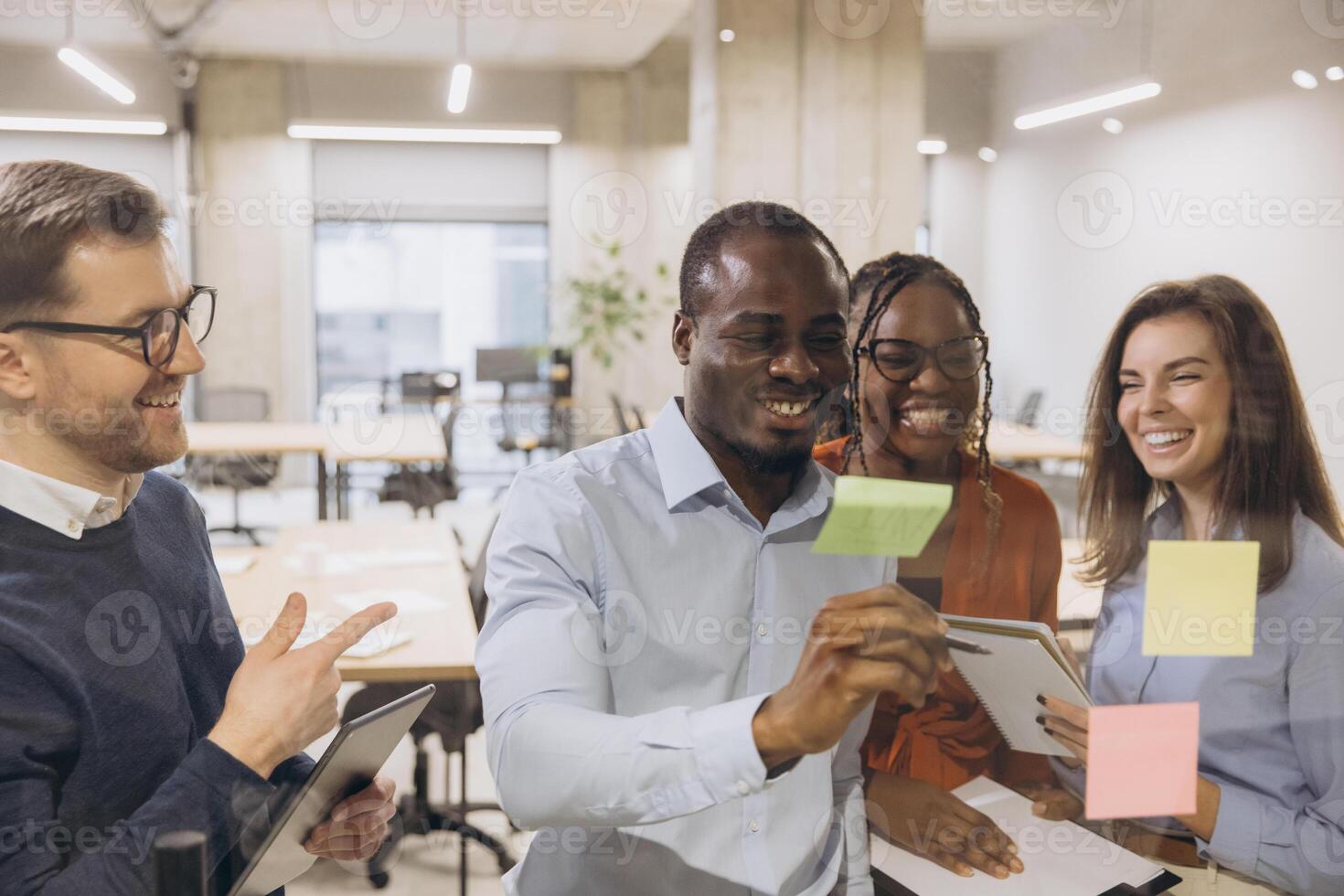 Diverse group of professionals brainstorming with sticky notes in a modern office. Teamwork and creativity in a collaborative workspace photo