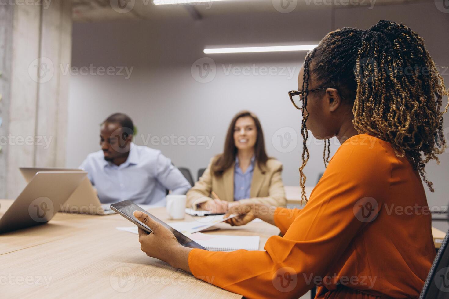 Business team working together on laptops, sharing ideas in modern workplace, representing inclusive corporate culture photo
