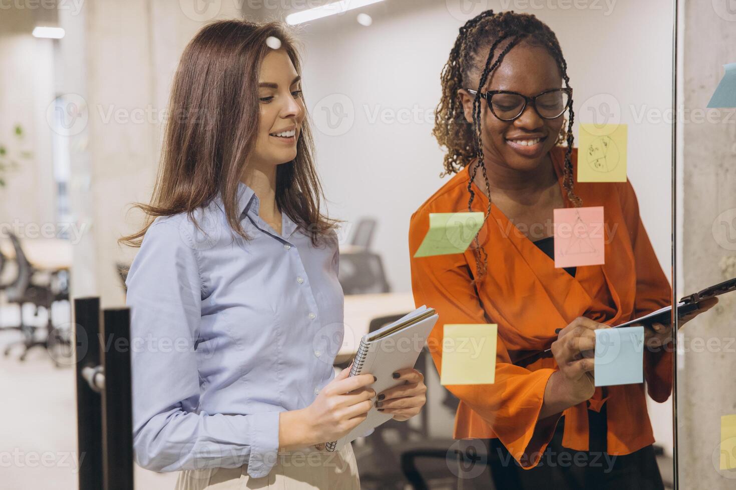 Business professionals collaborating, brainstorming project concepts while writing notes on glass board in contemporary workspace photo