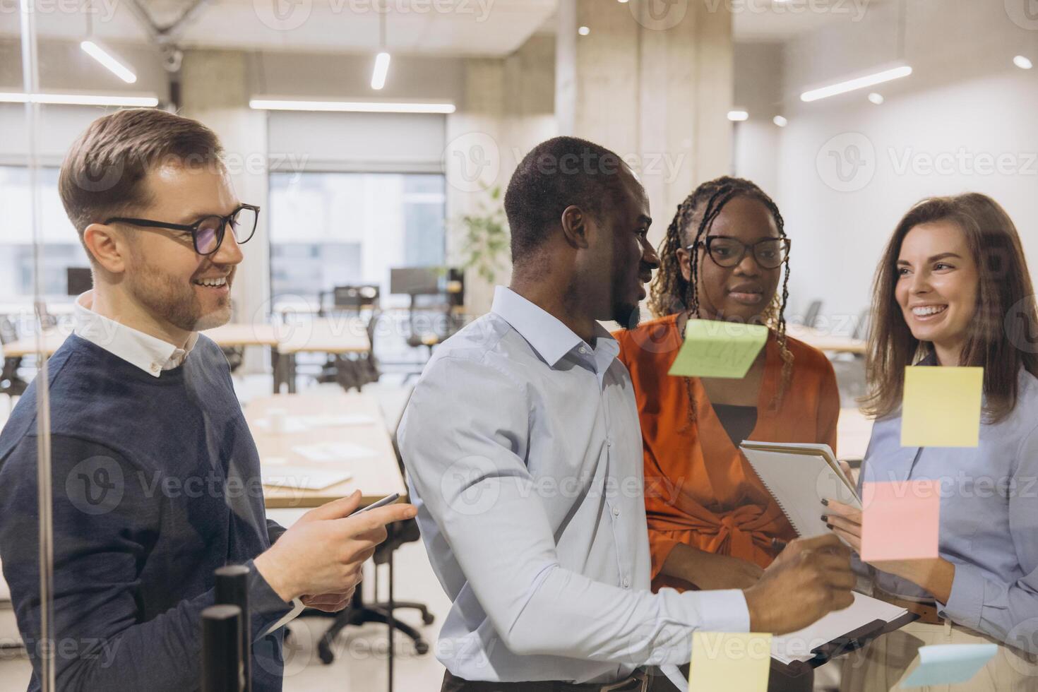 Group of professionals brainstorming with sticky notes in a contemporary office setting, showcasing teamwork and diversity in business photo