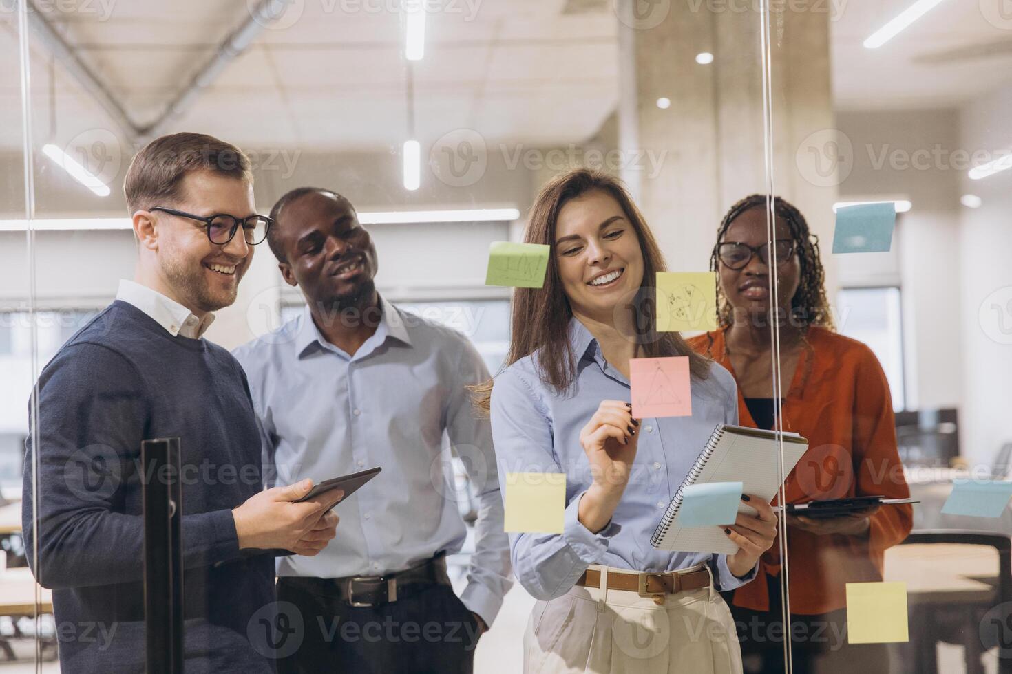 Group of professionals brainstorming in a contemporary office, using sticky notes and tablets for creative business planning and teamwork photo