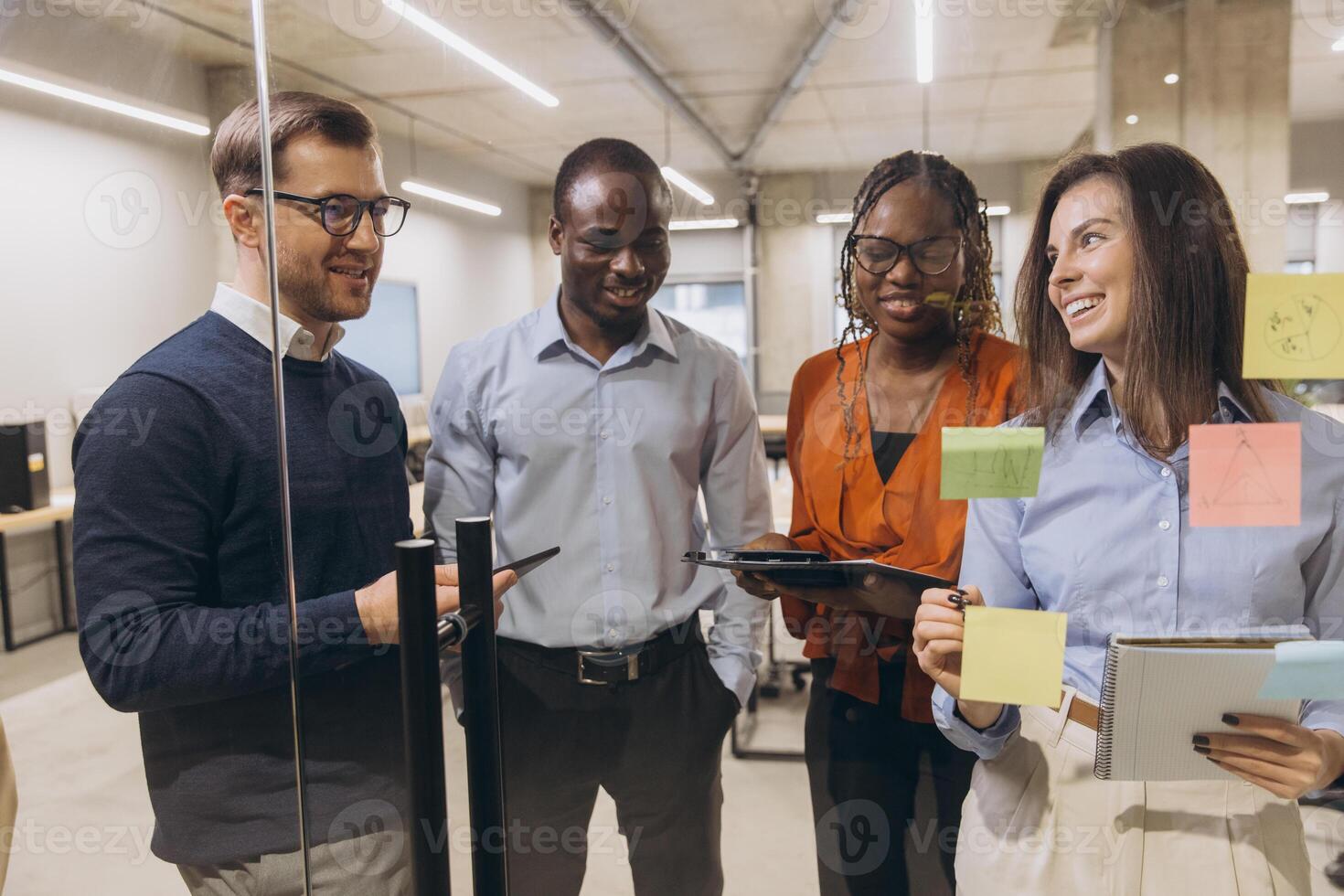 Business team brainstorming near glass whiteboard, sharing strategic insights during collaborative meeting in modern workspace photo