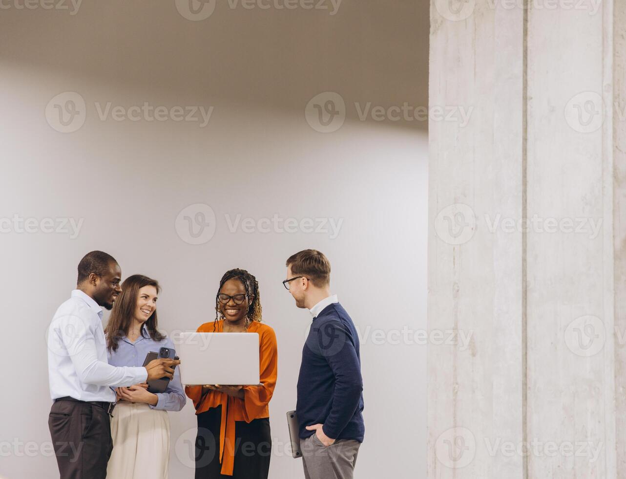 Diverse professional team collaborating, analyzing laptop project with engaged expressions in contemporary workplace environment photo