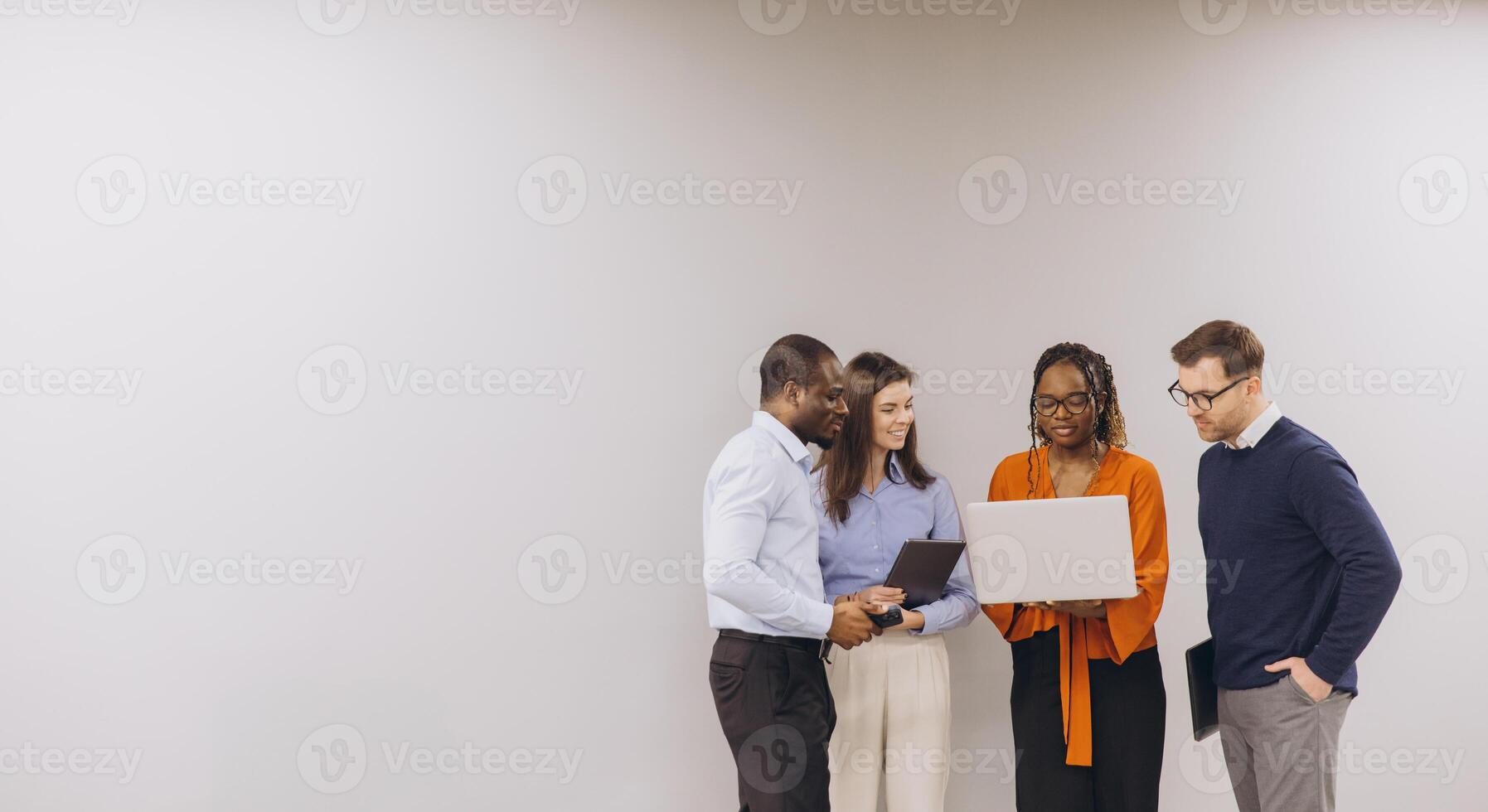 Interracial business team collaborating, leaning over laptop during professional meeting in modern office workspace photo