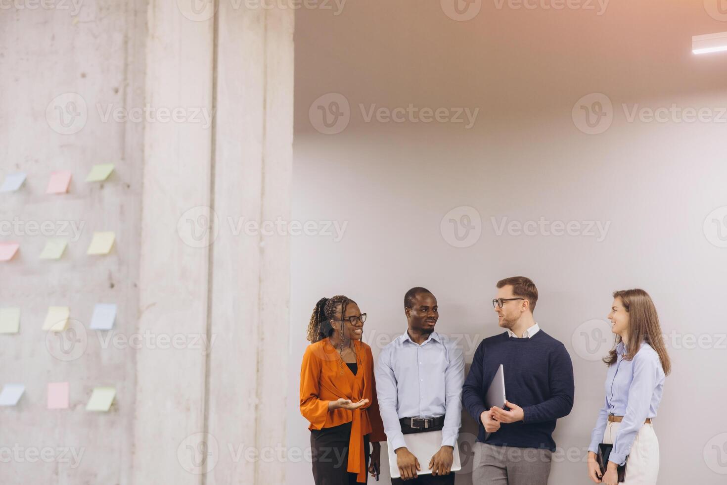 Diverse business team brainstorming near sticky note wall, collaborating dynamically in modern office environment, highlighting workplace communication photo