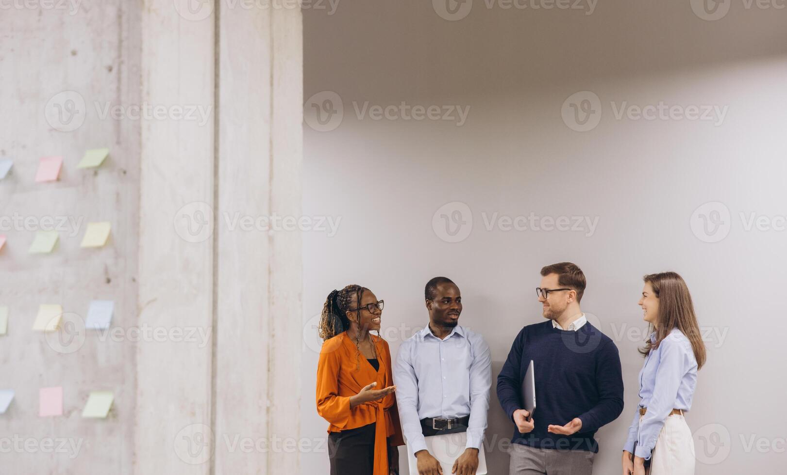 Business team collaborating, standing near sticky note wall, brainstorming innovative solutions with shared focus and energy photo