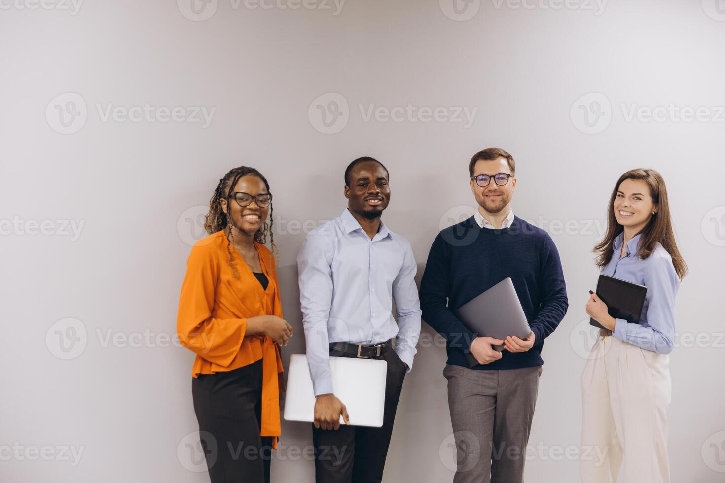 Diverse business team standing together in corporate workspace, working collaboratively with laptops, displaying professional unity and shared goals photo