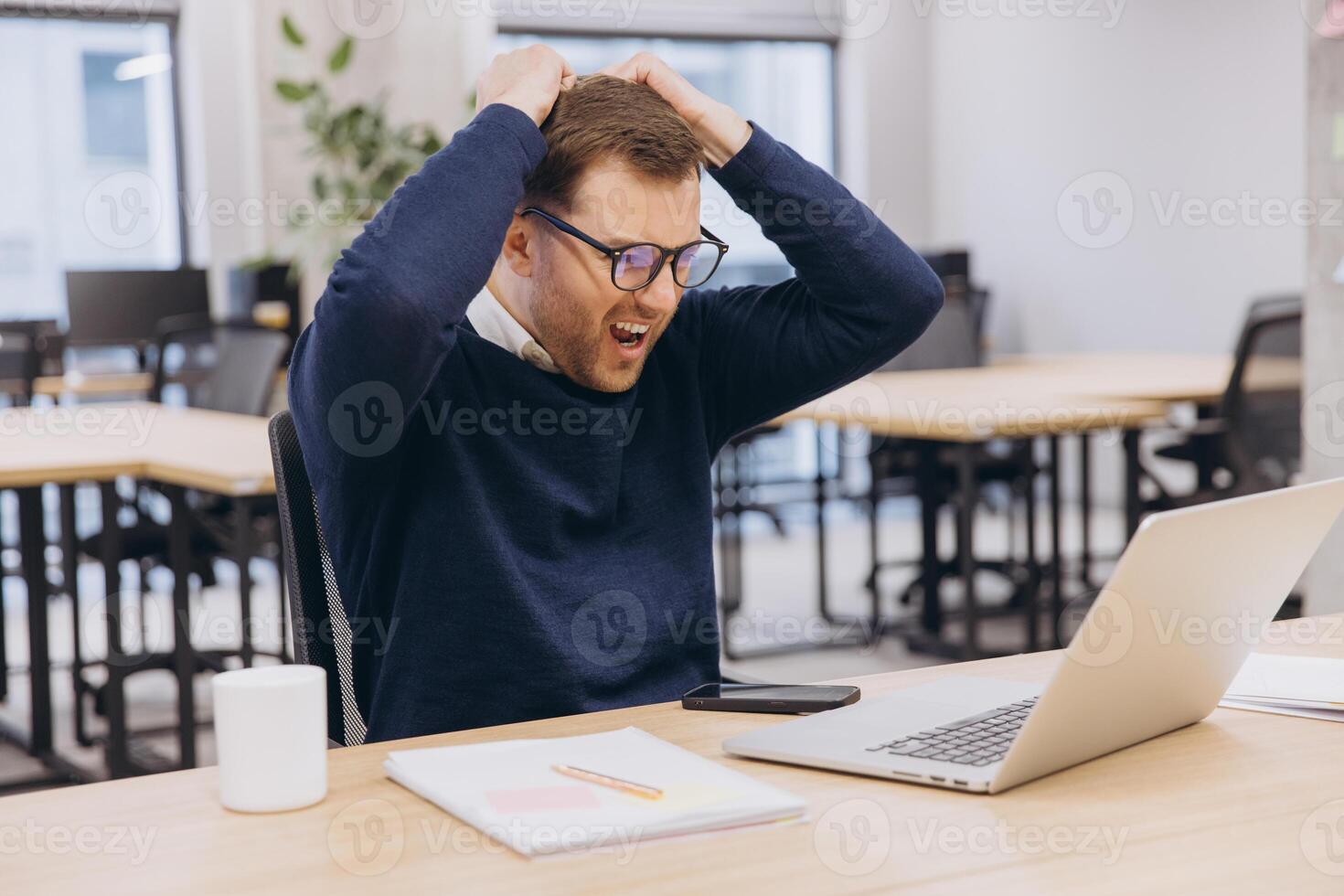 Businessman getting stressed and pulling his hair while working with his laptop in the office, he is screaming and shouting photo