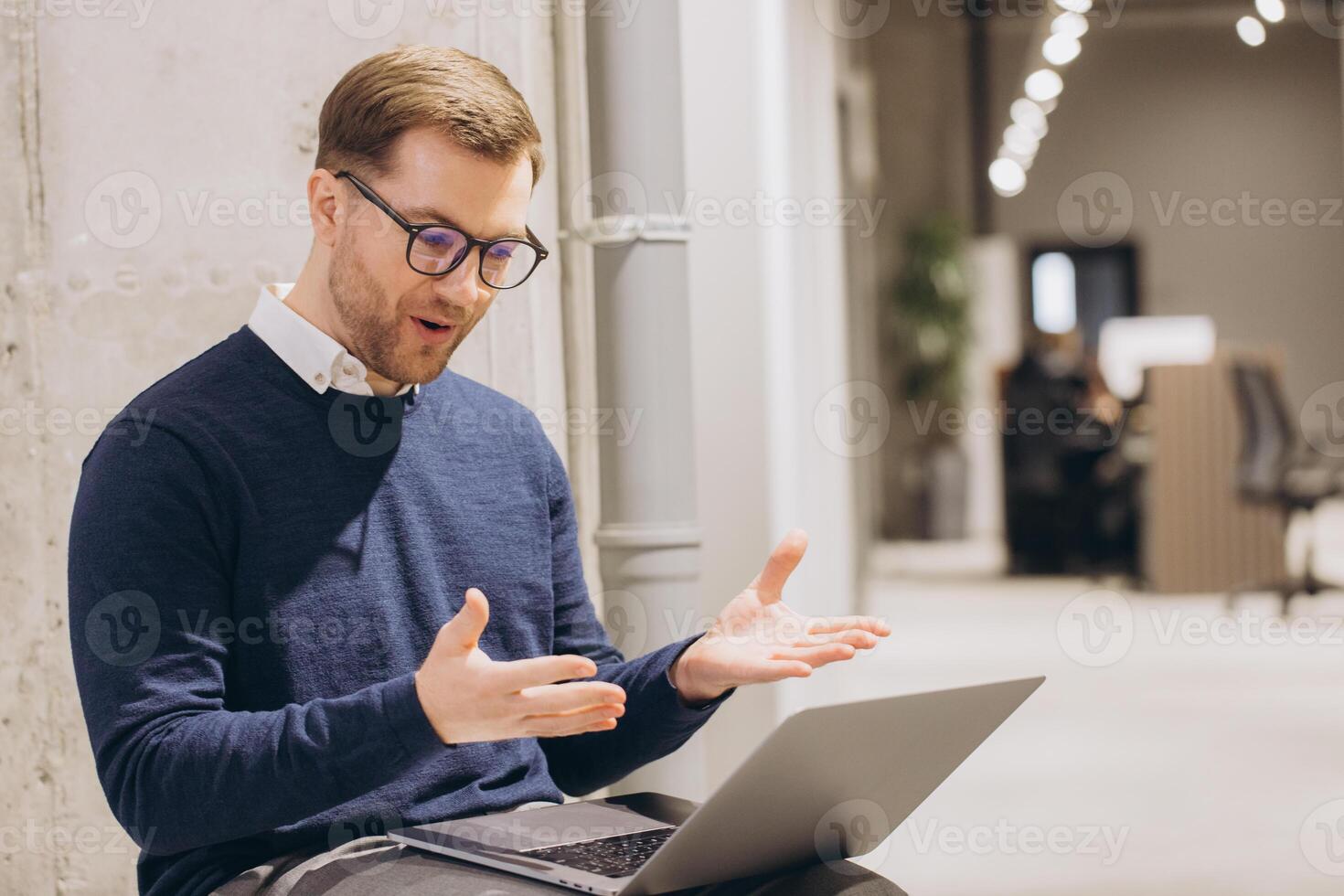 Businessman gesturing during a conference on a laptop, working in a modern office environment filled with natural light photo