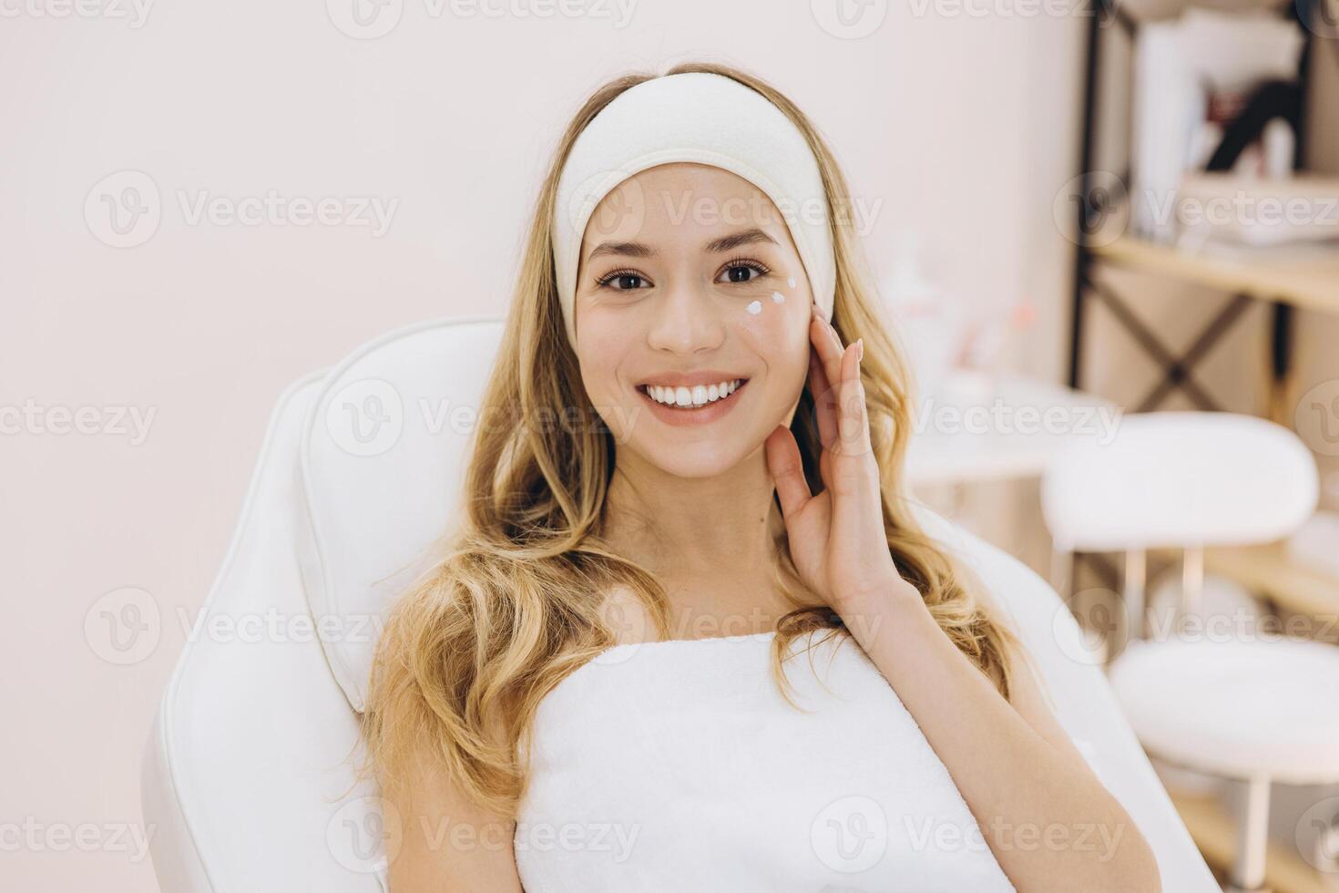Beautician spreading moisturizing cream on client's face during professional skincare treatment at spa photo