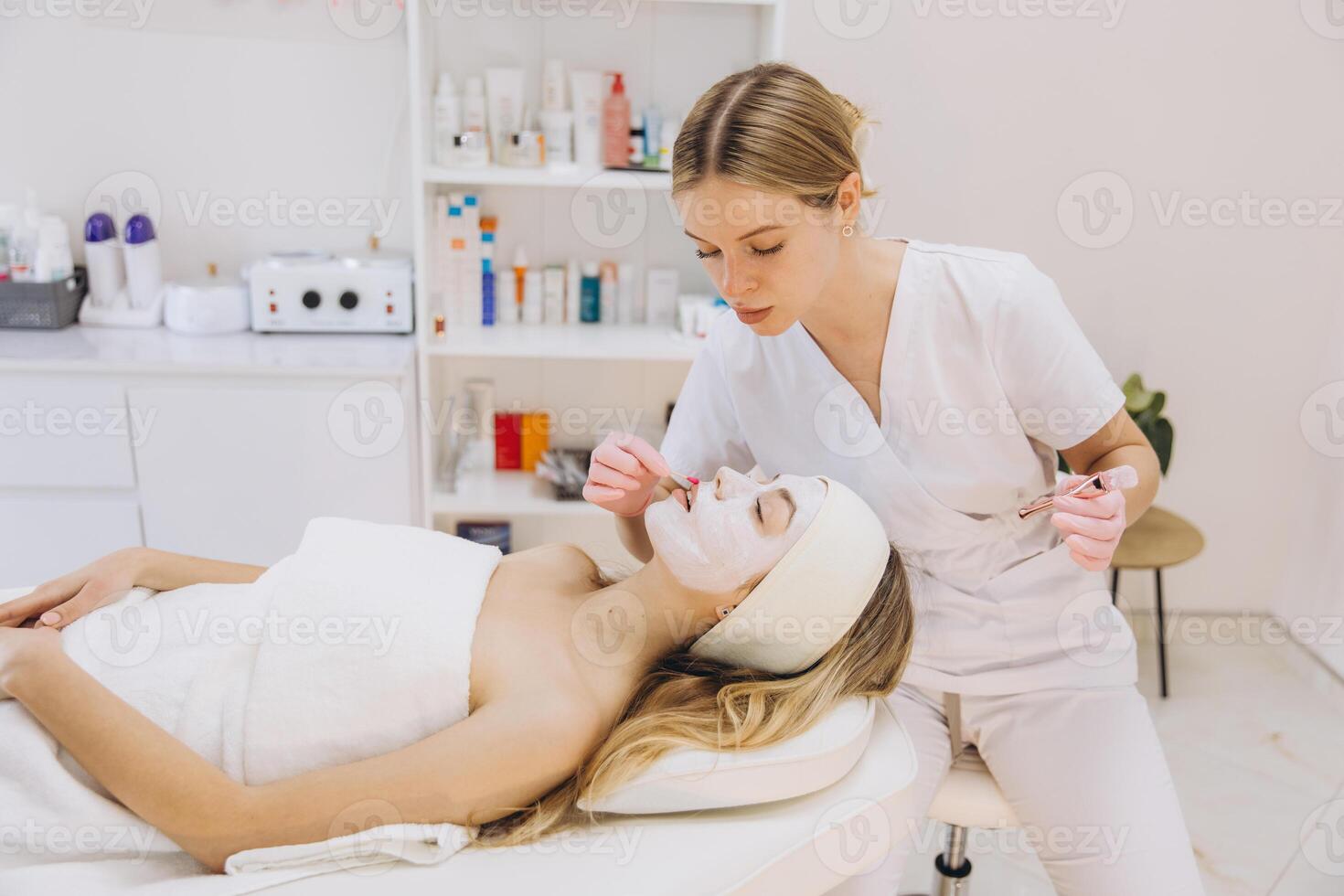 Esthetician applying facial mask on client, professional spa environment with skincare tools and calming ambiance photo