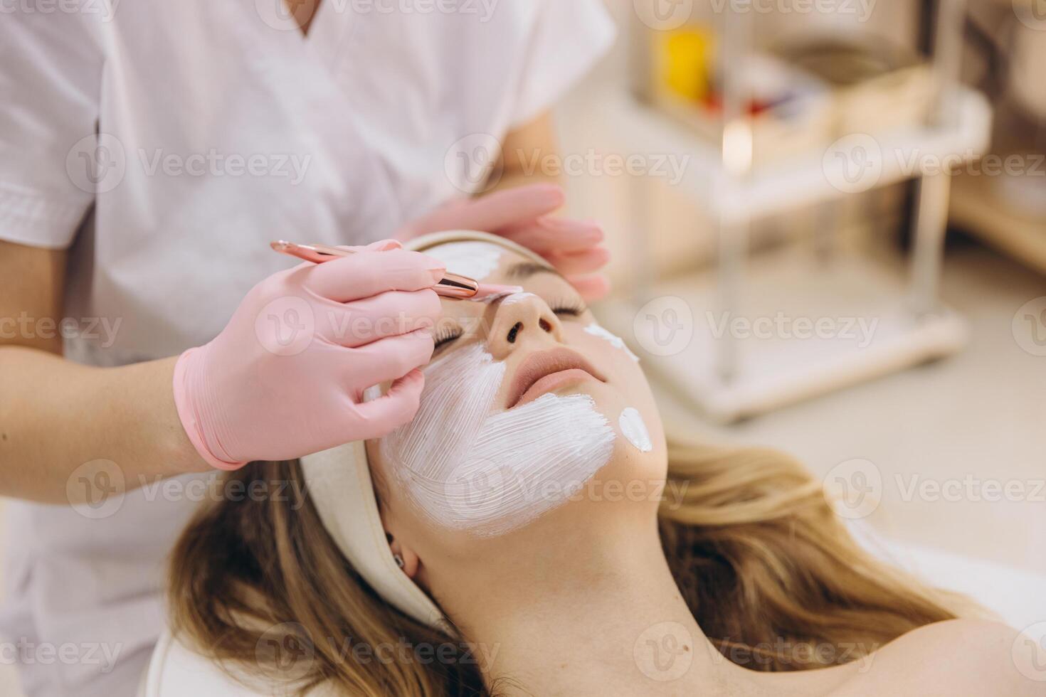 Beautician wearing gloves applies a facial mask to a client in a spa setting, emphasizing skincare and relaxation in a cosmetology practice photo