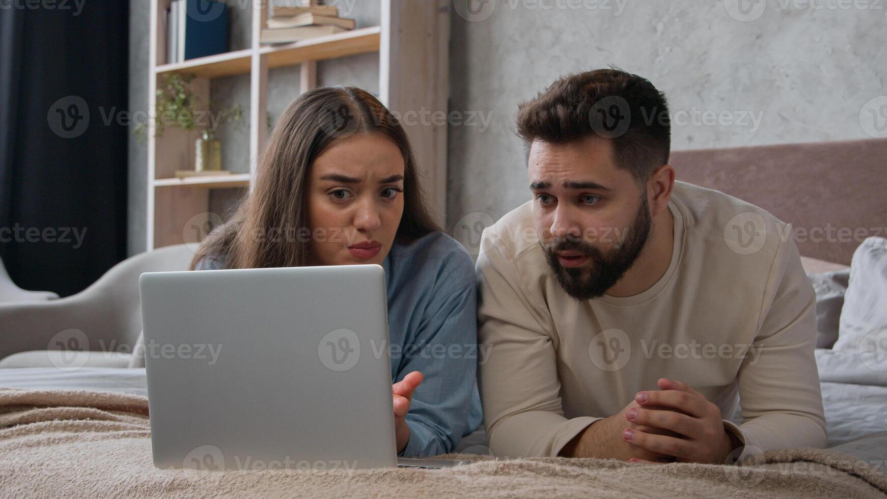 Caucasian upset couple husband wife worried shocked disappointed bad news loss negative result breakdown laptop internet service displeased woman girl and man guy in bedroom computer addicted failure photo