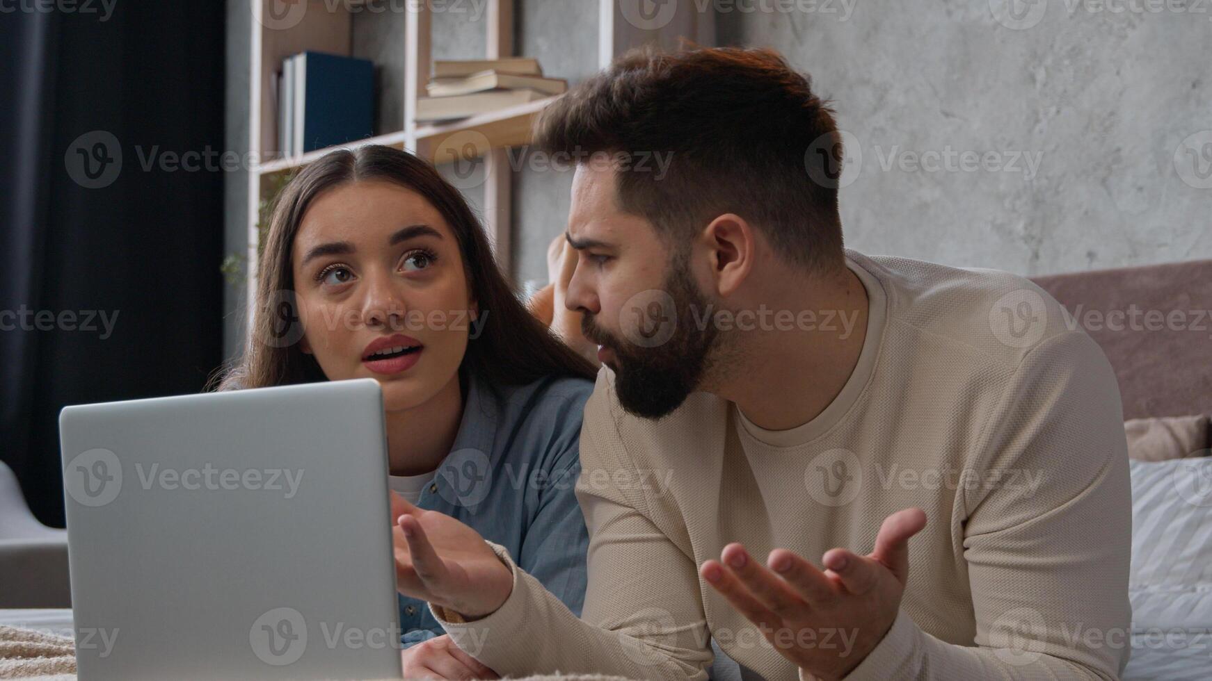 Relaxed couple family lying on bed use computer laptop online shopping together make order internet purchase choosing home goods for bedroom interior Caucasian woman man clients search delivery store photo