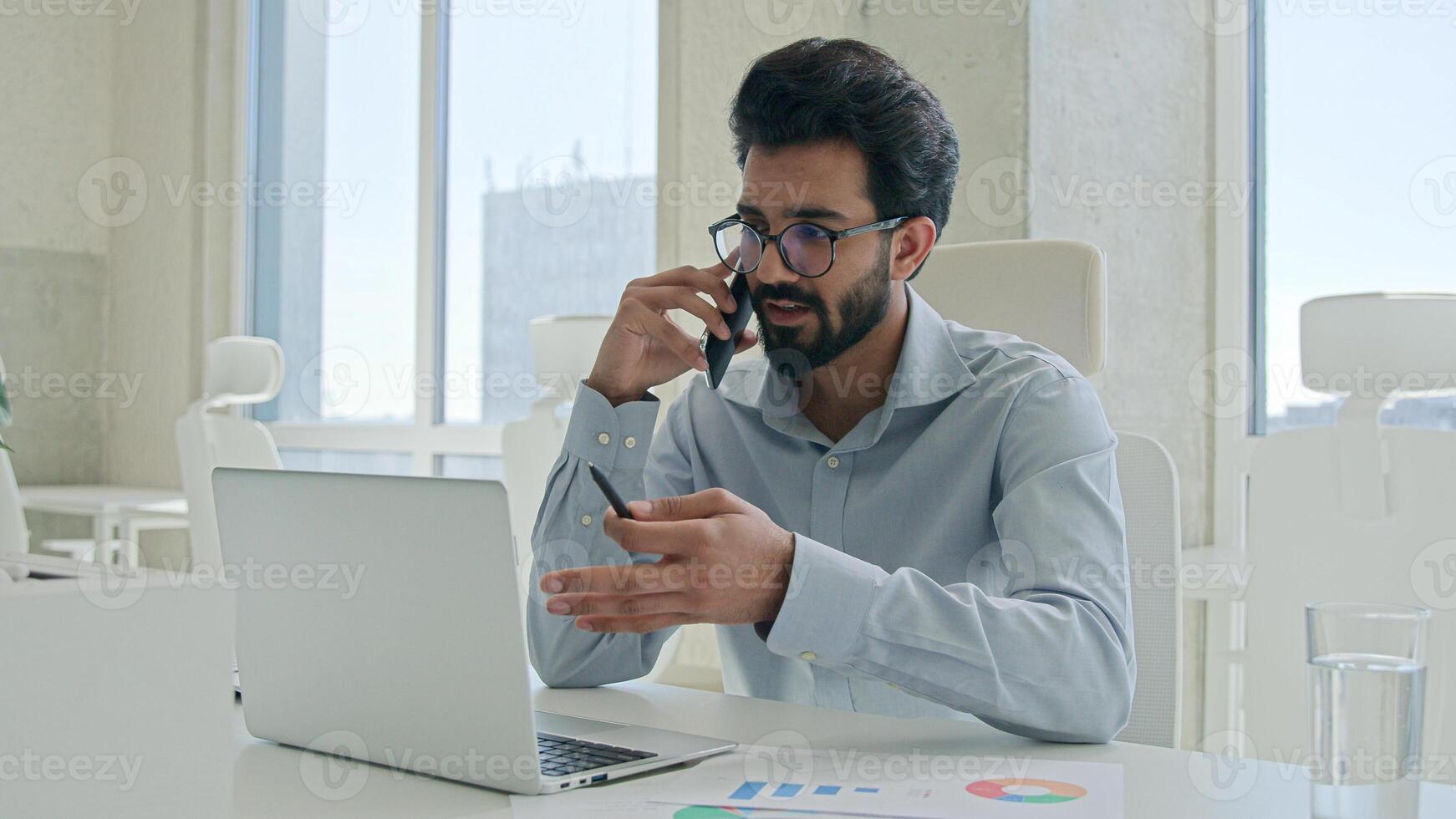 Successful Arabian businessman talking phone in office male professional executive manager employer Indian man friendly talk business call mobile conversation at workplace cellphone calling smiling photo