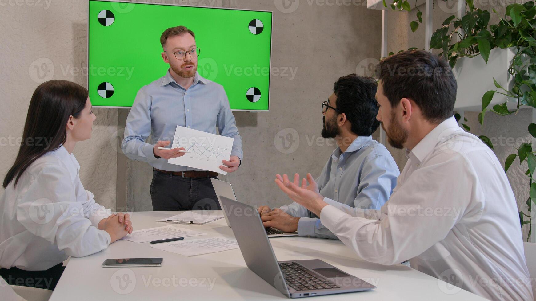 Male leader speaker coach talking to team multiracial men listen to CEO businessman teaching employees showing business presentation at group conference pointing at green interactive board chroma key photo