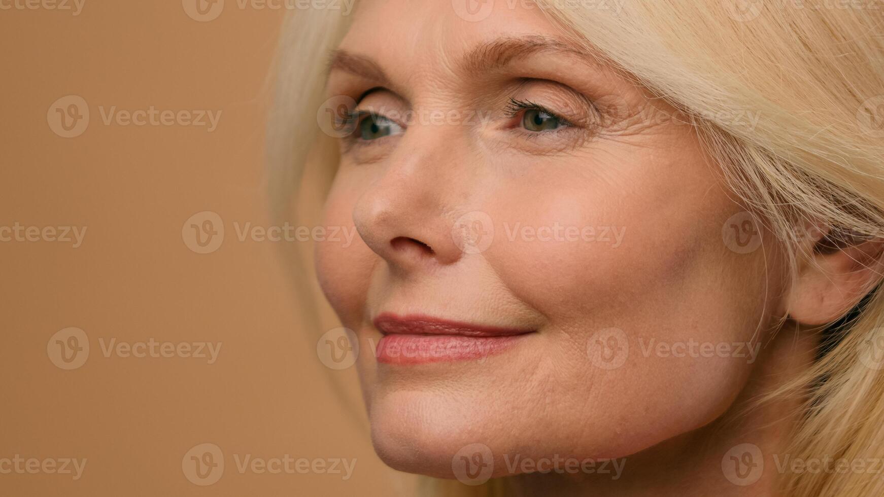 Close up female wrinkly smooth tighten face Caucasian mature senior 50s old woman touch perfect clean skin beauty anti-aging lifting cosmetics plastic surgery collagen rejuvenation on beige background photo