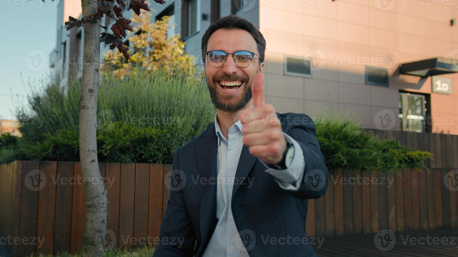 Caucasian happy successful businessman employer texting messages on mobile phone smiling man business entrepreneur using smartphone app browsing social network show thumb up approval gesture outdoors photo
