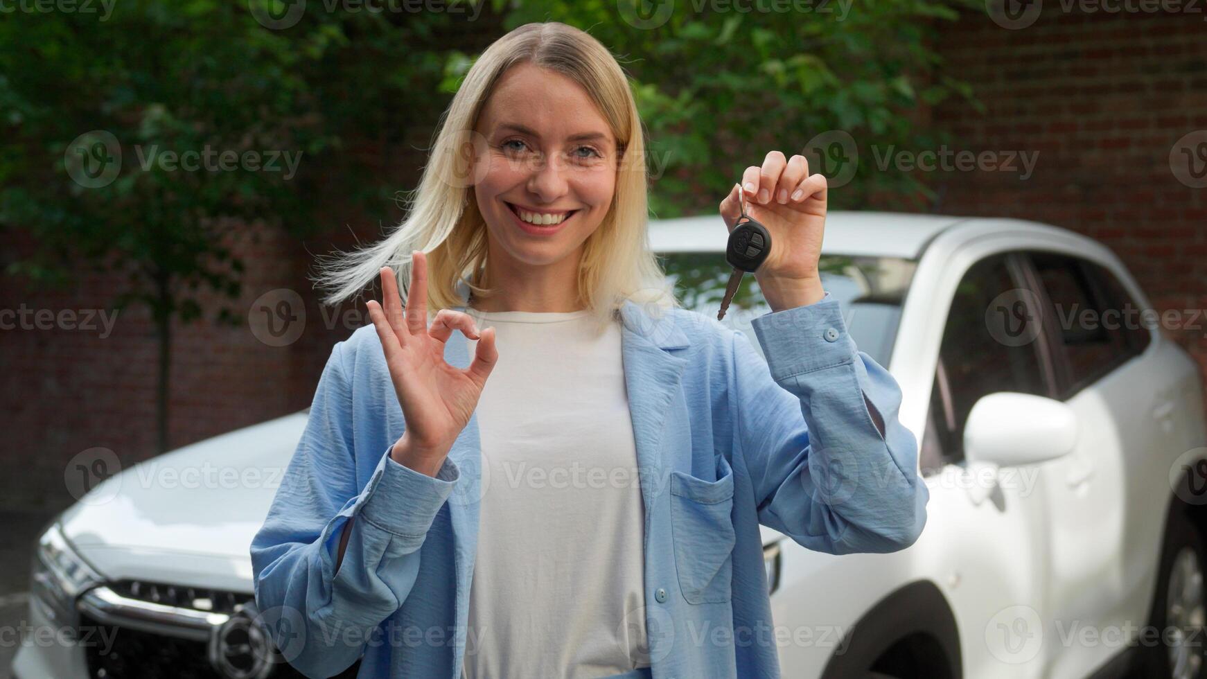 Glad happy Caucasian woman driver car buyer smile girl businesswoman showing automobile ignition key automobile owner gesturing ok sign hand in city vehicle rent service female purchase new transport photo